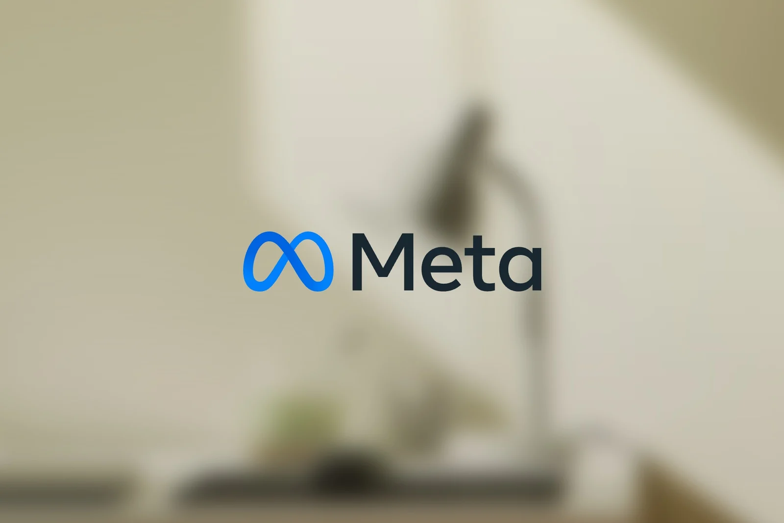 Bulanık, sıcak tonlu bir çalışma masası önünde Meta logosu